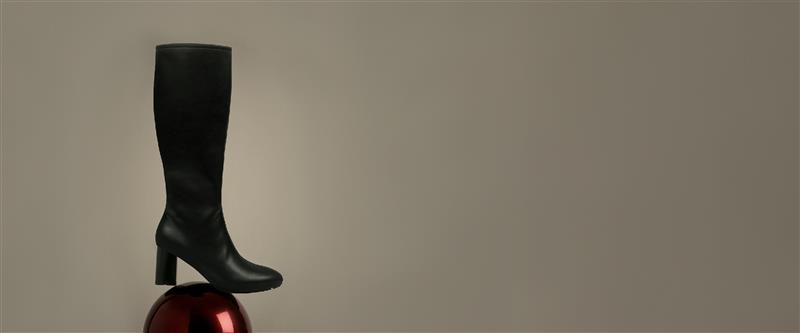 Black knee-high boot on a reflective surface with a neutral background. the holiday countdown. up to 40% off sitewide. excludes new arrivals. shop now